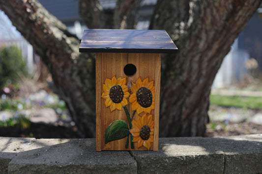 I'll say it again I love sunflowers! These beauties are on a natural cedar background speckled in gold. The flowers are raised carved, and hand painted with dark stained roof. Made of weather and insect resistant cedar, wood glue, polyacrylic sealed and easy bottom cleanout. 6 1/4" L x 5 1/2" W x 12" H.